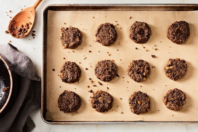 Twelve dark chocolate cookie circles sit on a cooking sheet.